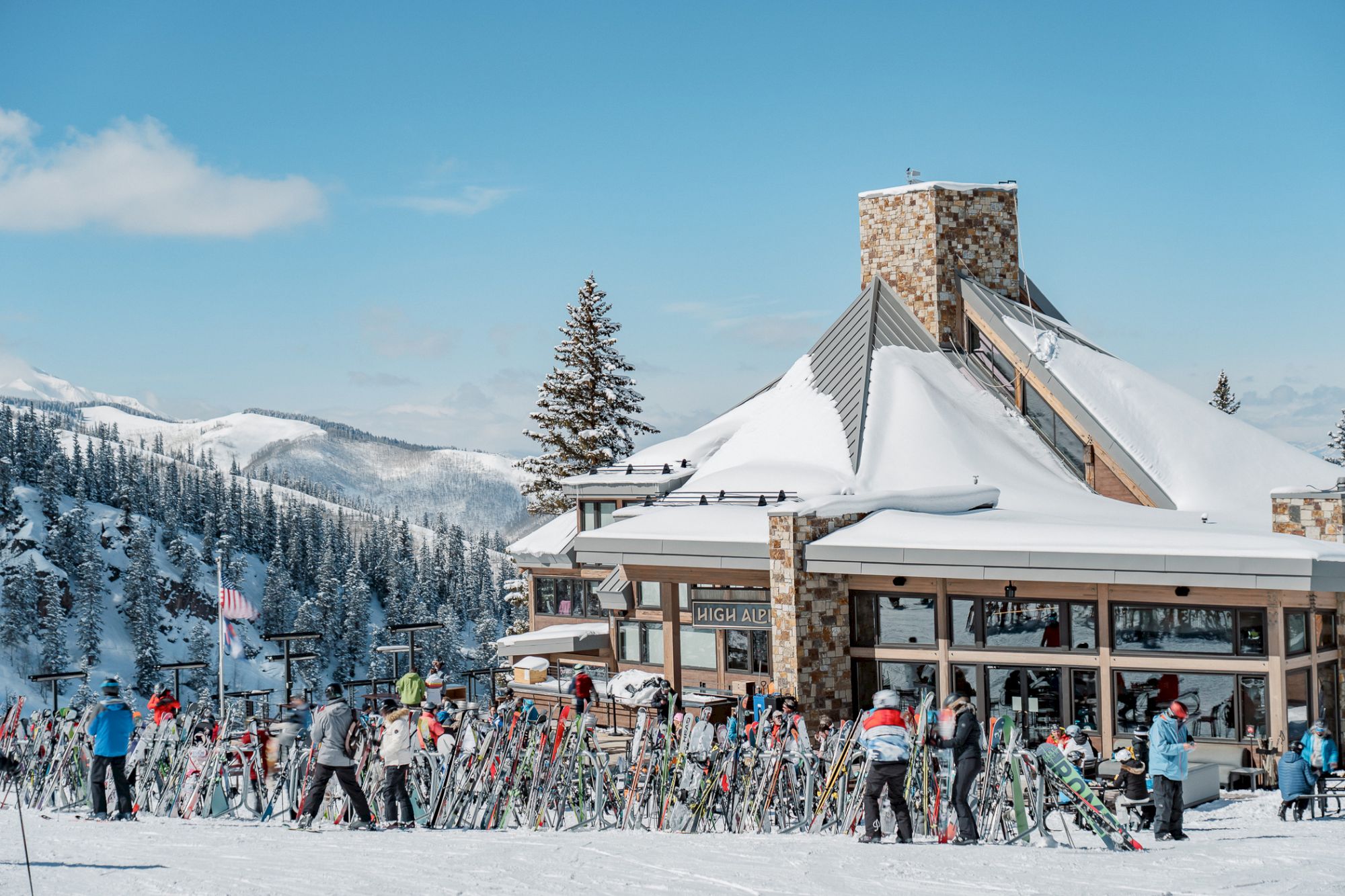 The image shows a winter ski resort with snow-covered mountains, a lodge, and people enjoying skiing and snow activities.