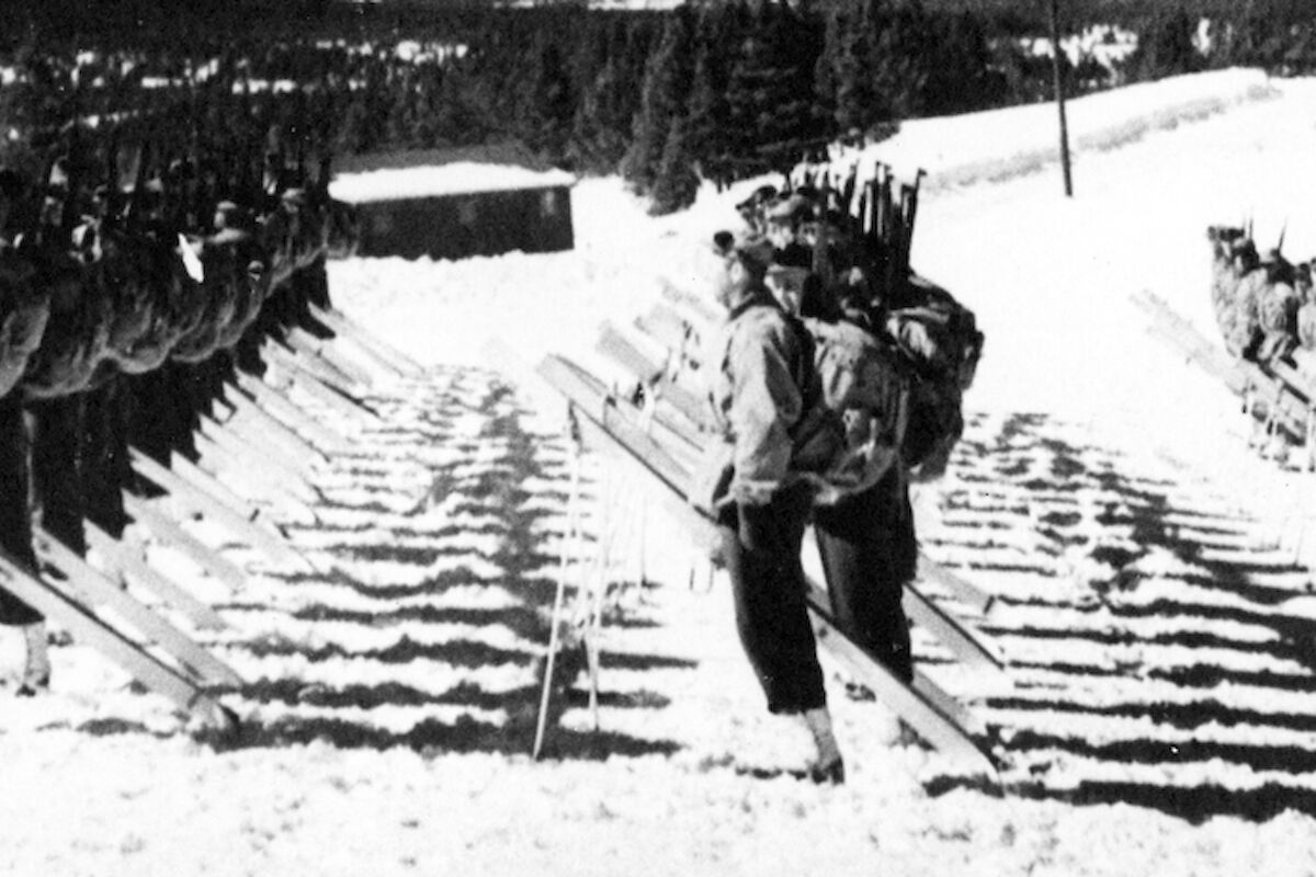 The image shows a group of soldiers marching in the snow near train tracks, likely during a historical military movement.