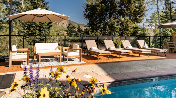 A poolside seating area with lounge chairs, umbrellas, and a wooden deck.