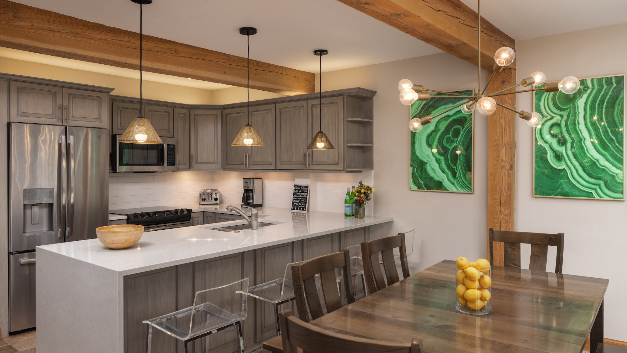 This image features a modern kitchen with gray cabinetry, a dining table, and vibrant green wall art. It's bright and inviting.